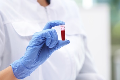 Photo of Scientist holding test tube with blood sample in laboratory