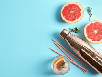 Photo of Flat lay composition with glass of infused water, grapefruits and bottle on color background. Space for text