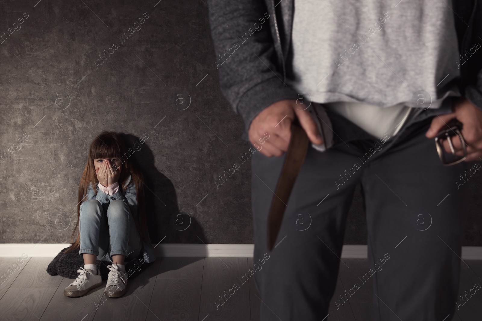 Photo of Man with unzipped pants and scared little girl indoors. Child in danger