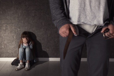 Photo of Man with unzipped pants and scared little girl indoors. Child in danger