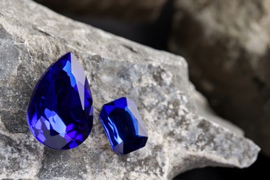 Photo of Two beautiful blue gemstones for jewelry on stone surface, closeup. Space for text