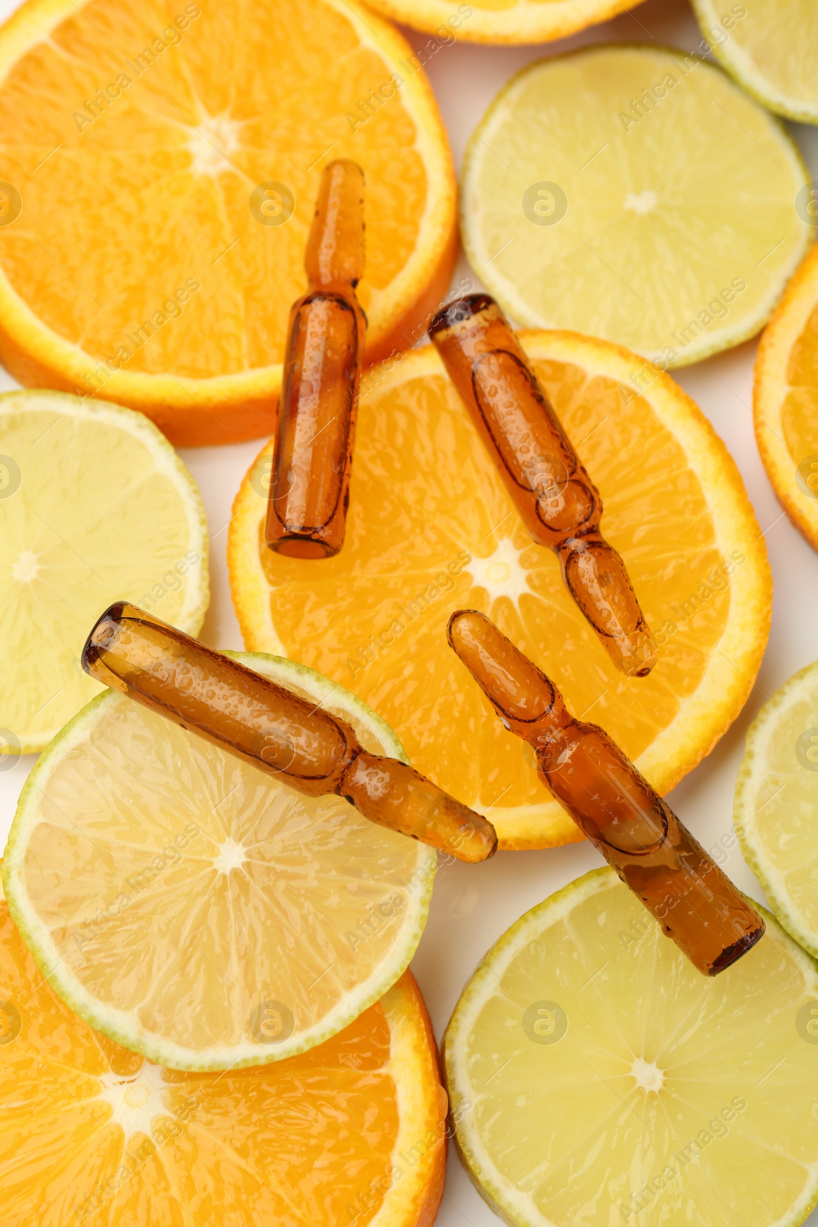 Photo of Skincare ampoules with vitamin C, lemon and orange slices on white background, flat lay