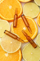 Photo of Skincare ampoules with vitamin C, lemon and orange slices on white background, flat lay