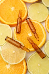 Skincare ampoules with vitamin C, lemon and orange slices on white background, flat lay