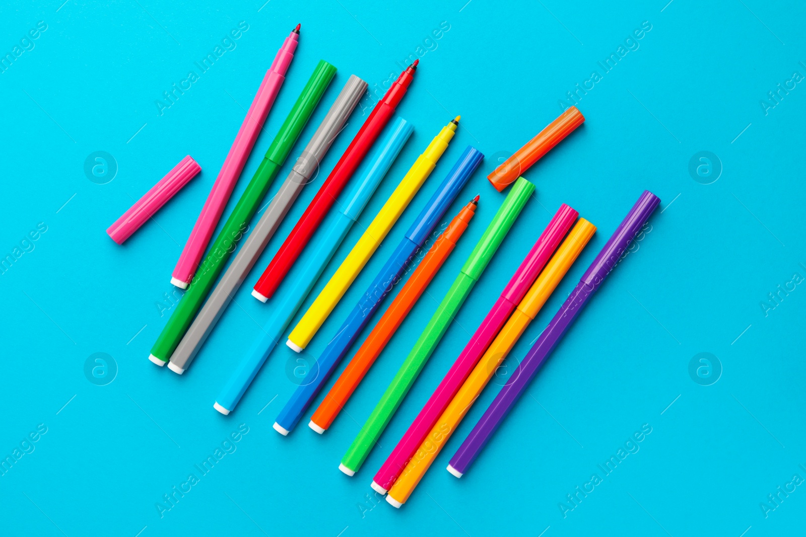 Photo of Many bright markers on light blue background, flat lay