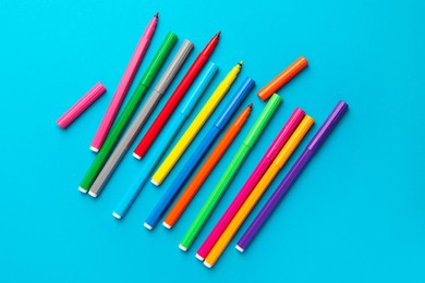 Many bright markers on light blue background, flat lay