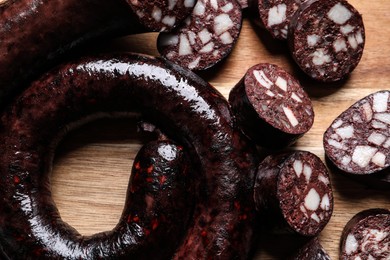 Photo of Cut tasty blood sausages on wooden background, flat lay