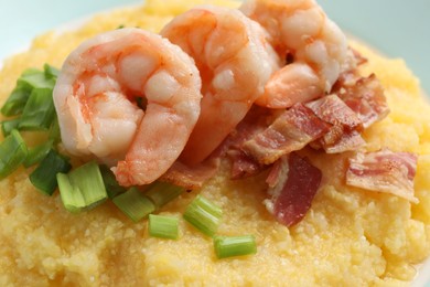 Photo of Fresh tasty shrimps, bacon, grits and green onion on plate, closeup