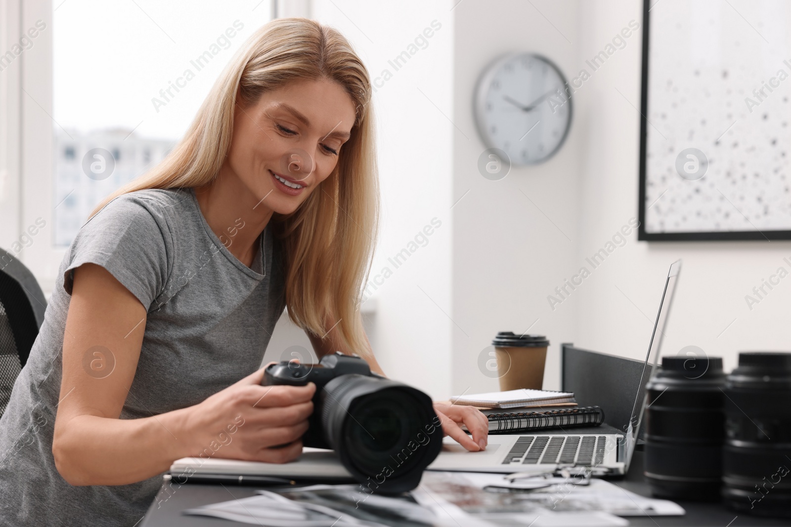 Photo of Professional photographer with digital camera at table in office