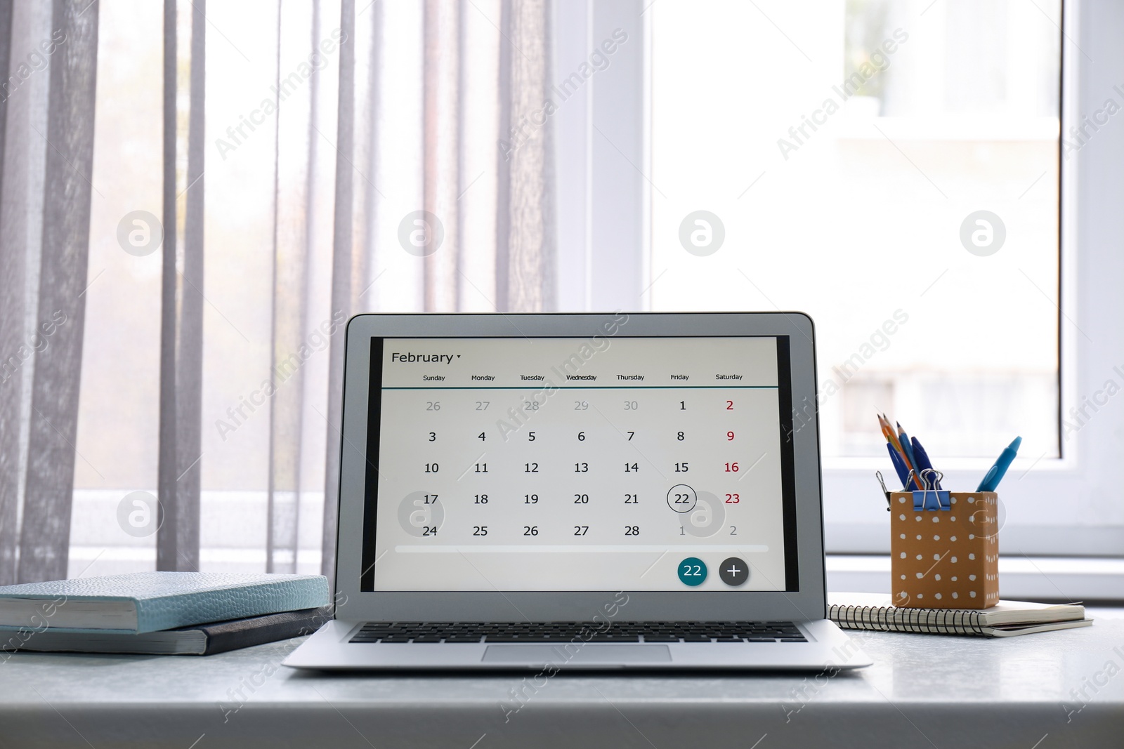 Photo of Modern laptop with calendar on screen in office