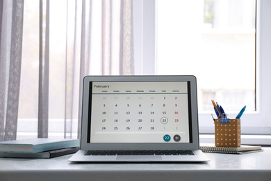 Modern laptop with calendar on screen in office