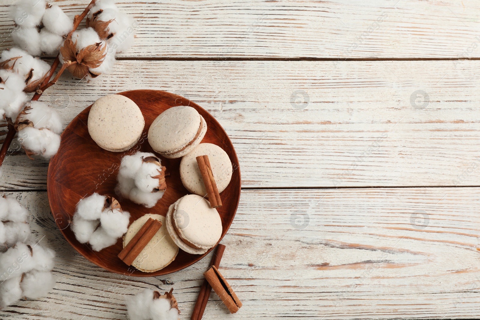 Photo of Delicious macarons and cotton flowers on white wooden table, flat lay. Space for text