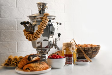 Photo of Traditional Russian samovar and treats on white table