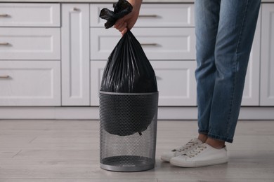 Photo of Woman taking garbage bag out of bin at home, closeup