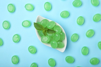 Flat lay composition with tasty mint candies and leaves on color background