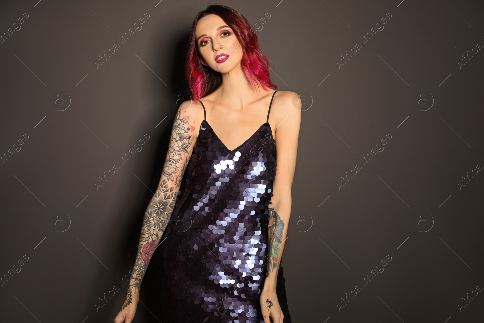 Photo of Beautiful woman with tattoos on arms against black background