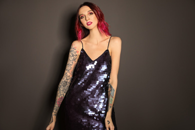 Photo of Beautiful woman with tattoos on arms against black background