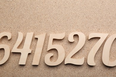 Photo of Many wooden numbers on fiberboard, flat lay