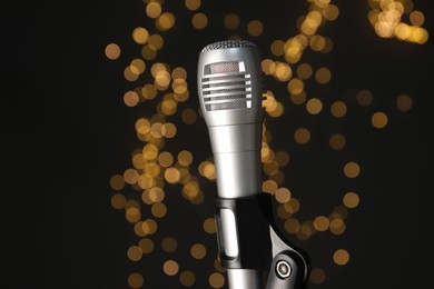 Photo of Microphone against black background with blurred lights, closeup. Sound recording and reinforcement