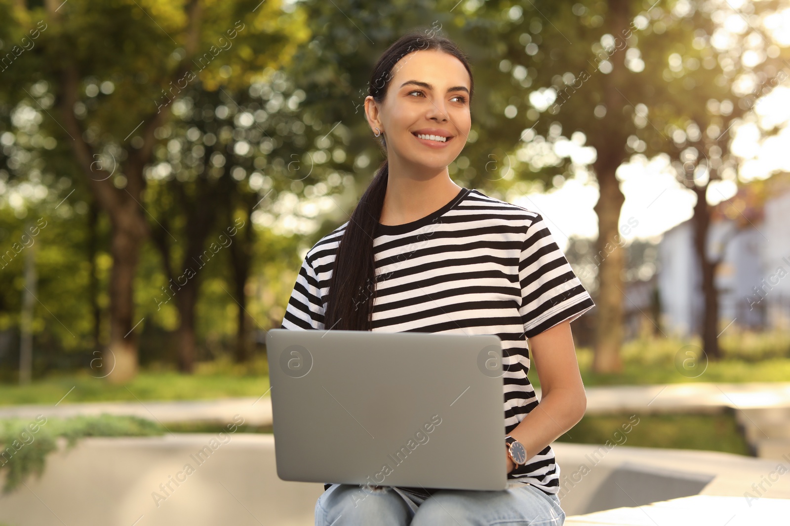 Photo of Happy young woman using modern laptop outdoors