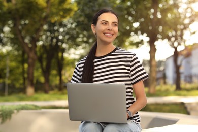 Happy young woman using modern laptop outdoors