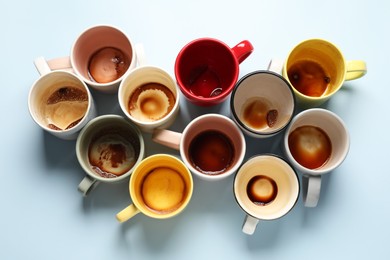 Many dirty cups after drinking coffee on light blue table, flat lay