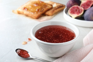 Photo of Delicious fig jam on light grey table, closeup