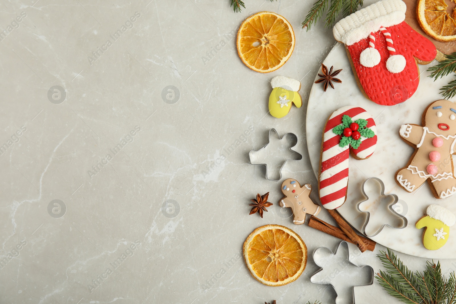 Photo of Flat lay composition with decorated Christmas biscuits and cookie cutters on light table. Space for text