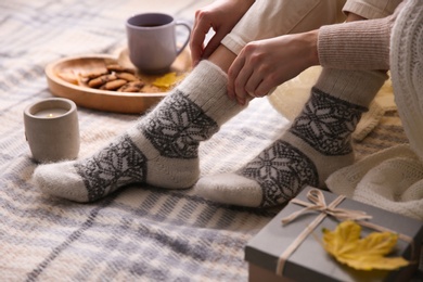 Photo of Woman wearing warm socks on checkered plaid, closeup. Cozy season