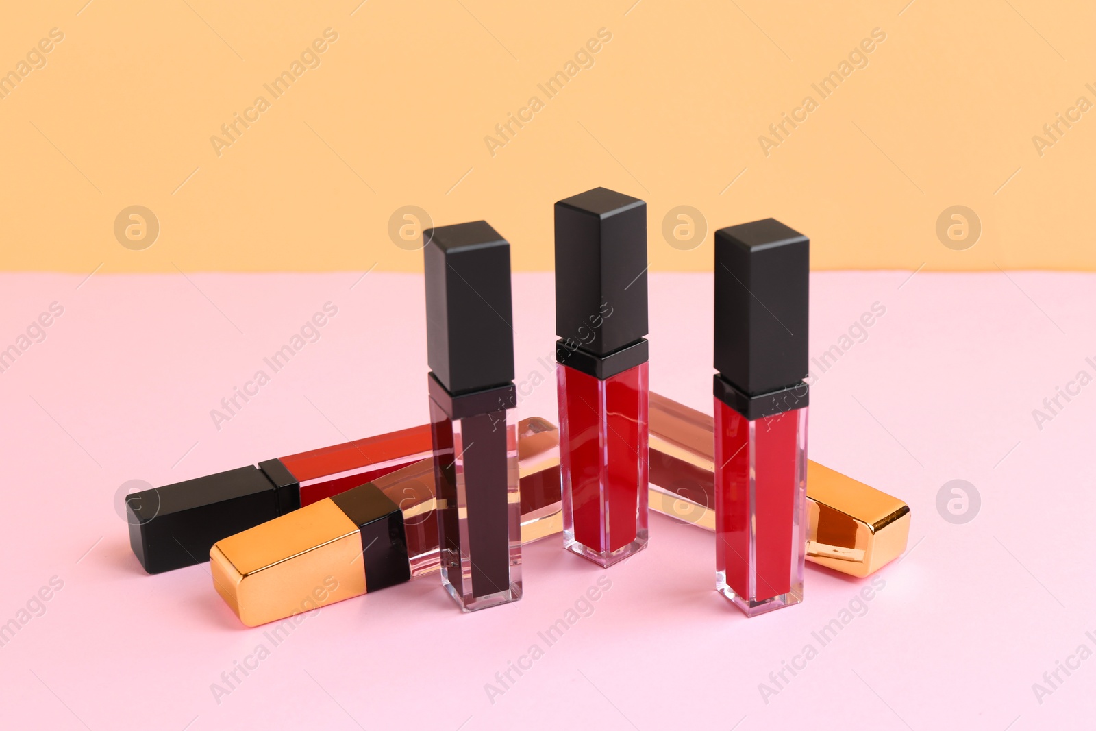 Photo of Many different lip glosses on color background