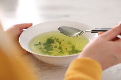 Photo of Woman eating tasty soup at white marble table, closeup