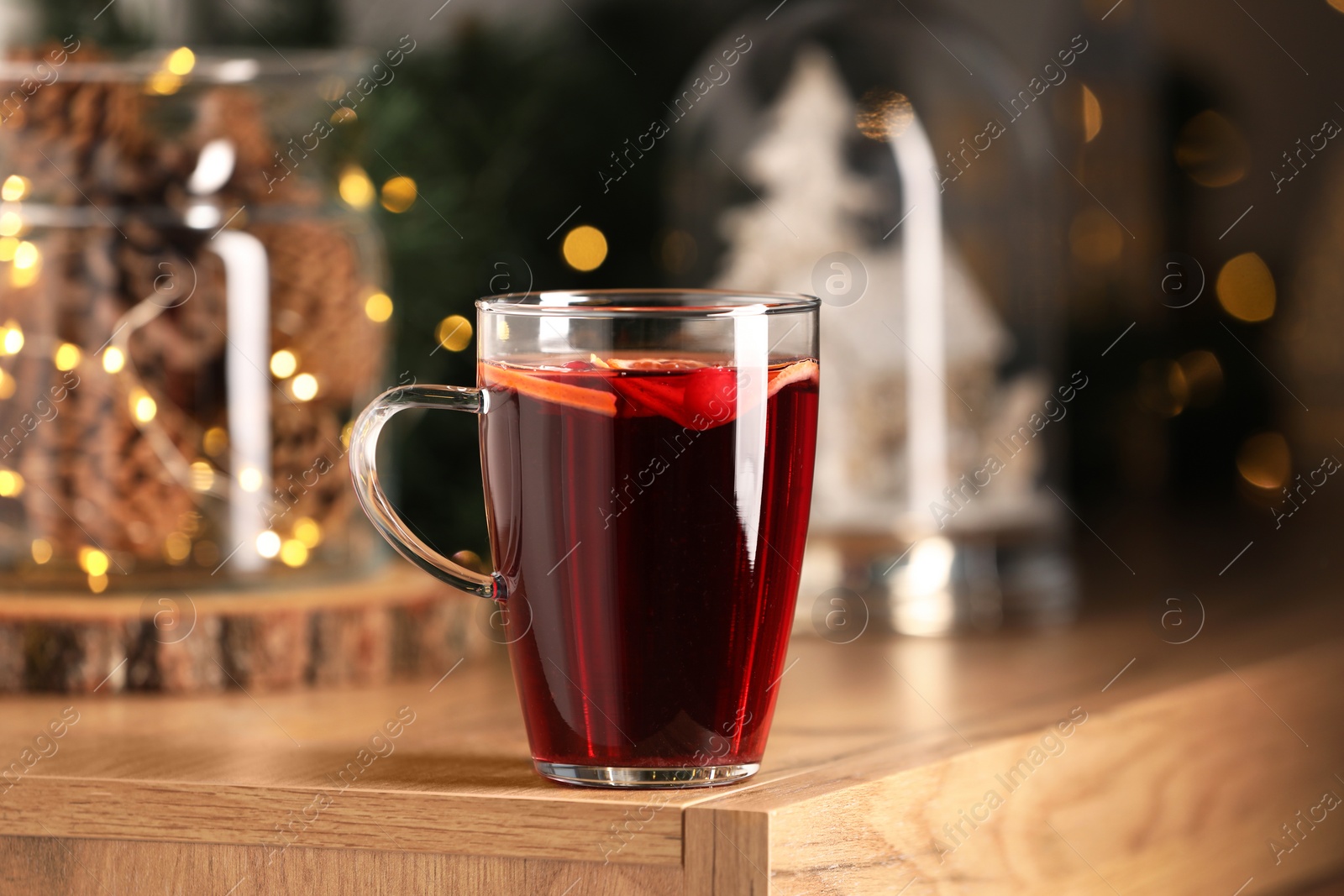 Photo of Delicious mulled wine in glass cup on wooden table, closeup