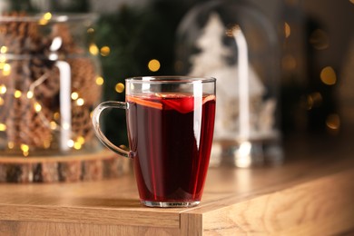 Photo of Delicious mulled wine in glass cup on wooden table, closeup