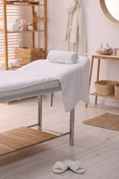 Comfortable massage table with clean towels in spa center