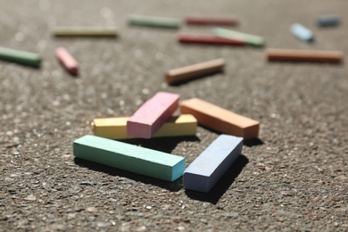 Many colorful chalk sticks on asphalt, closeup