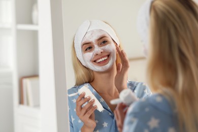 Photo of Young woman applying face mask at home, space for text. Spa treatments