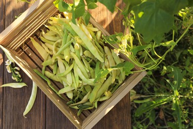 Crate with fresh green beans on wooden table in garden, top view