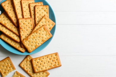 Photo of Delicious crackers on white wooden table, flat lay. Space for text