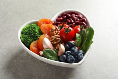 Photo of Bowl with products for heart-healthy diet on grey table