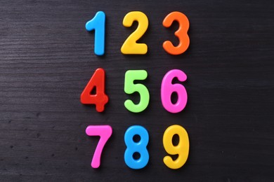 Colorful numbers on dark wooden school desk, flat lay