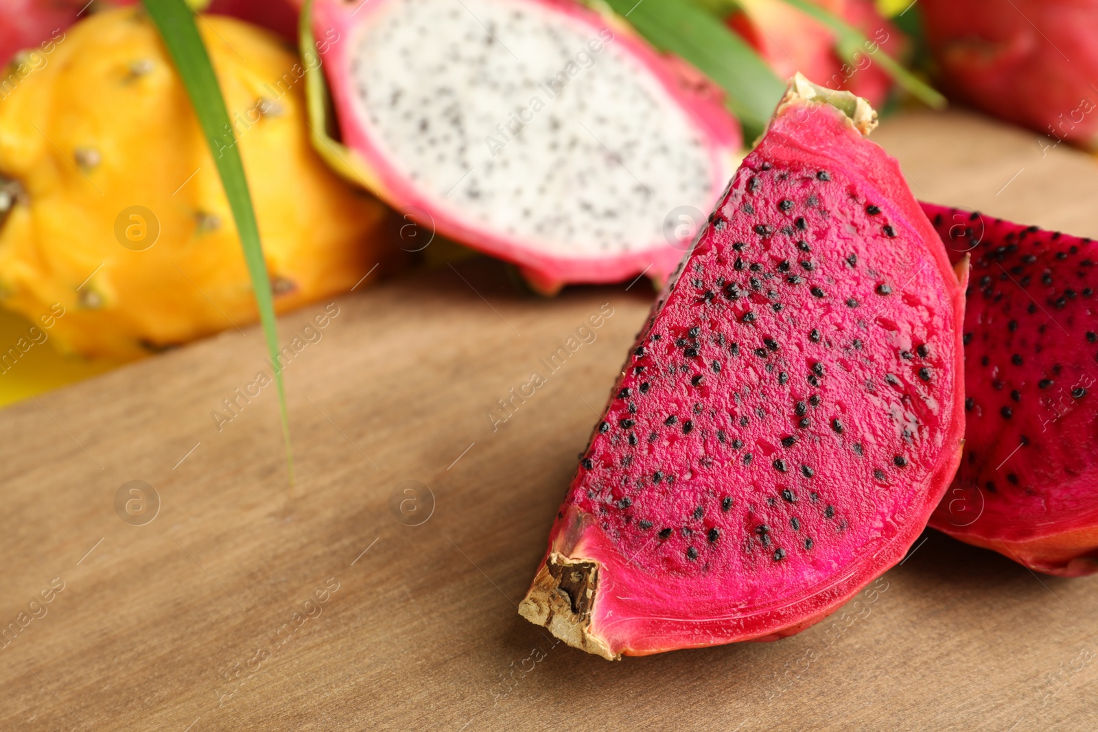 Photo of Delicious cut red pitahaya fruit on wooden board, closeup. Space for text