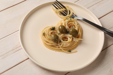Photo of Heart made of tasty spaghetti, fork, olives and cheese on light wooden table