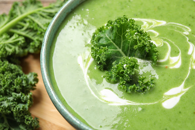 Photo of Tasty kale soup with cream on table, closeup