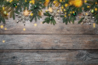 Photo of Christmas greeting card with space for text. Flat lay composition of fir tree branches and festive decor on wooden background