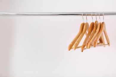 Photo of Clothes rail with wooden hangers on white background