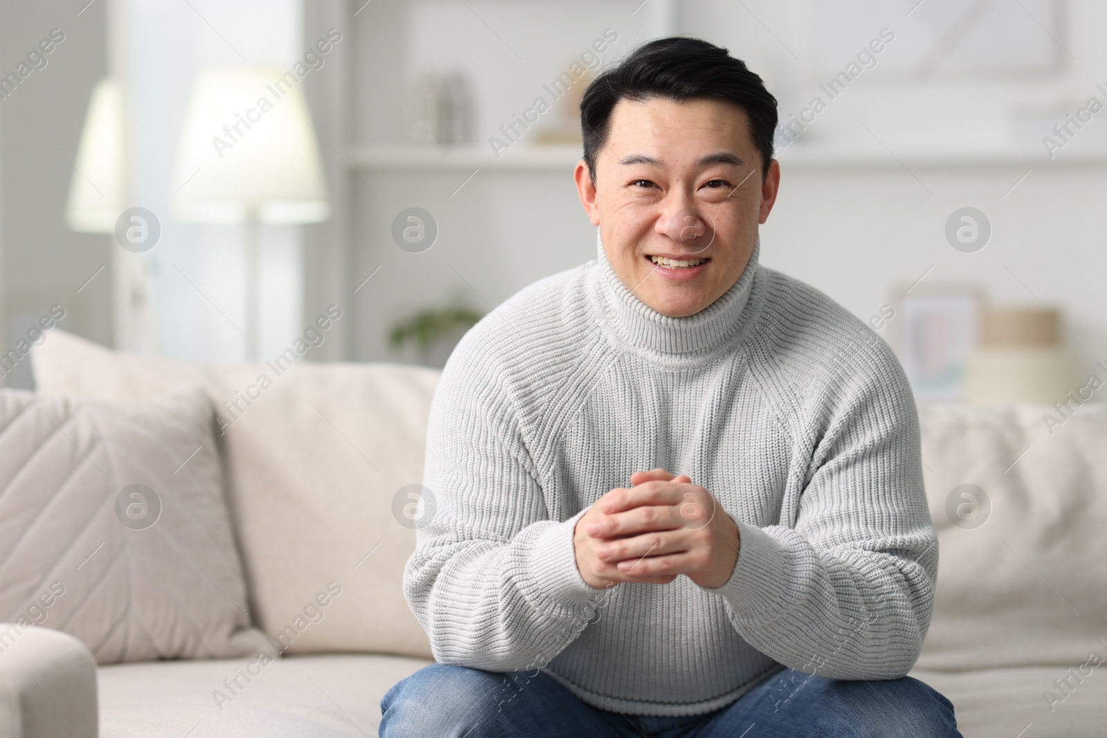 Photo of Portrait of smiling man on sofa indoors. Space for text