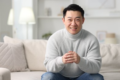 Portrait of smiling man on sofa indoors. Space for text