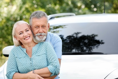 Happy senior couple posing near car outdoors