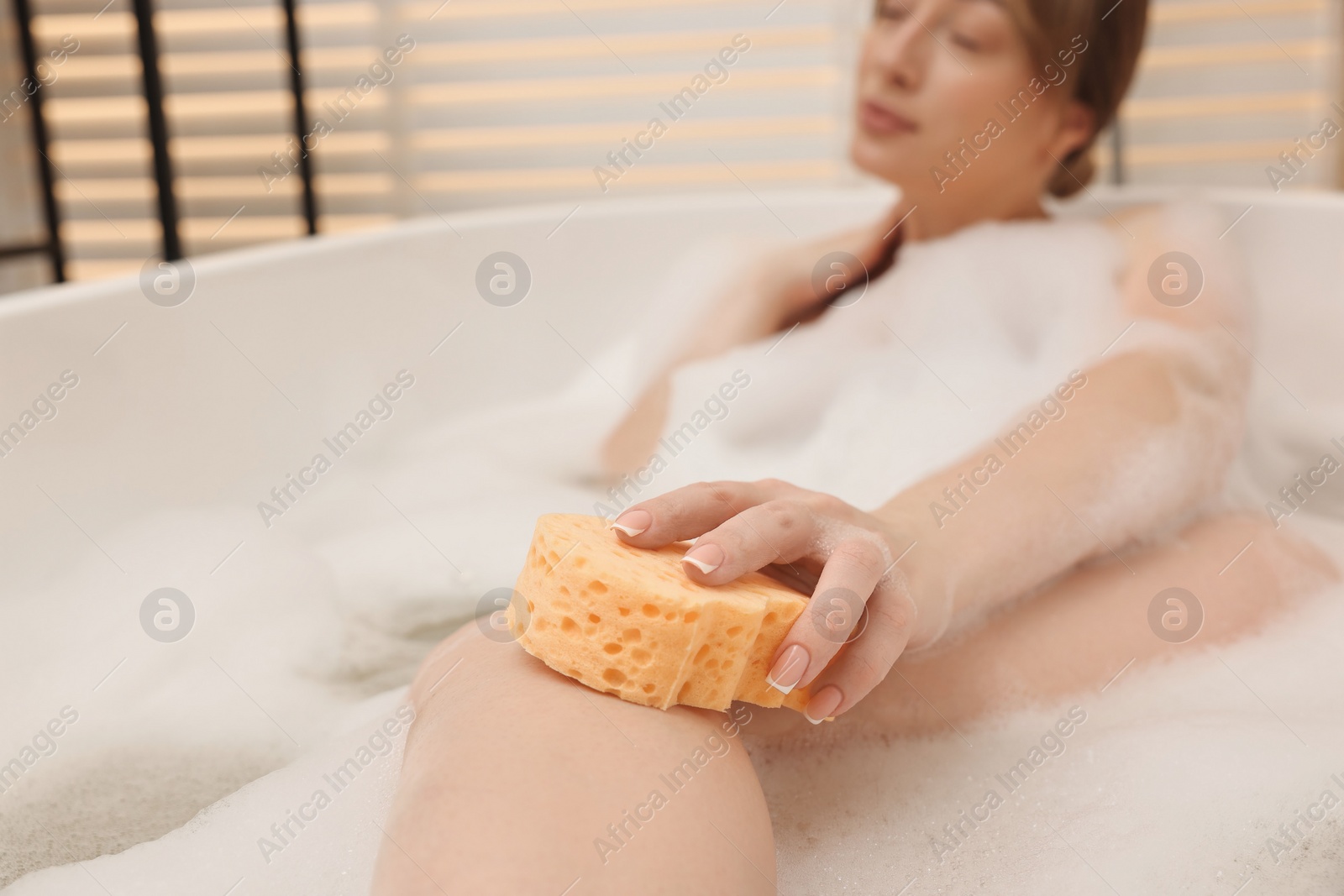 Photo of Woman taking bath with foam in tub indoors, selective focus