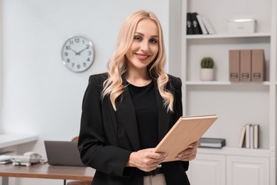 Portrait of happy secretary with notebook in office